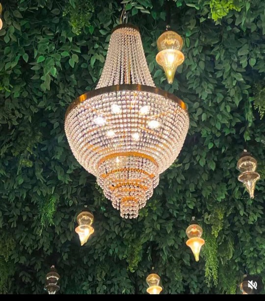 Elegant home decoration with artificial flowers, a golden vase, handcrafted accessories, and warm decorative lighting.