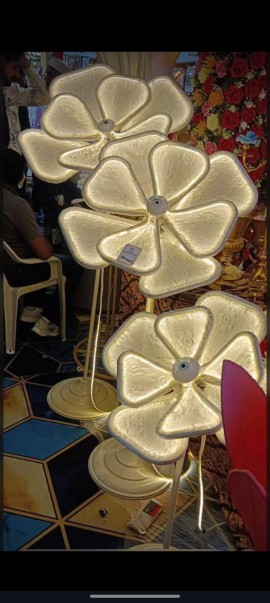 Warm fairy lights and decorative LED lighting illuminating an elegant event stage with artificial flowers.